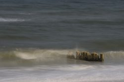 Welle bricht an Buhnen